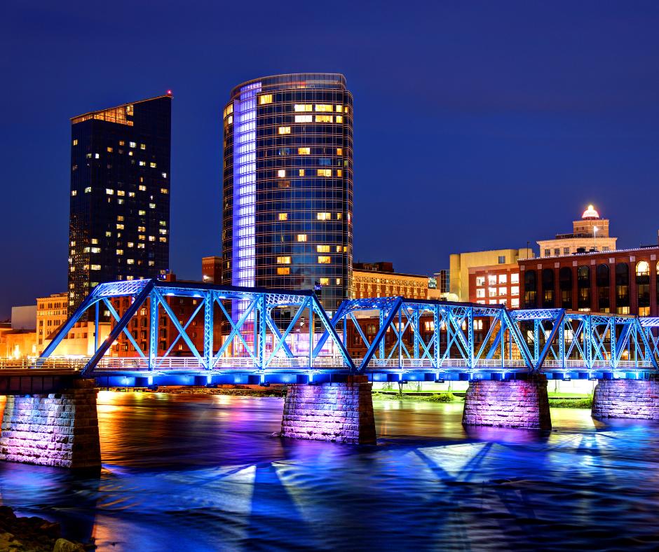 Photo of the skyline in Grand Rapids, Michigan at night with lights on a bridge and the Grand River