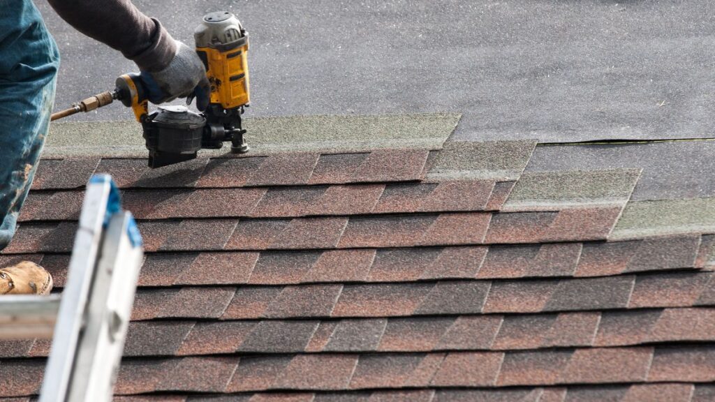 Roofer nails shingles to a roof