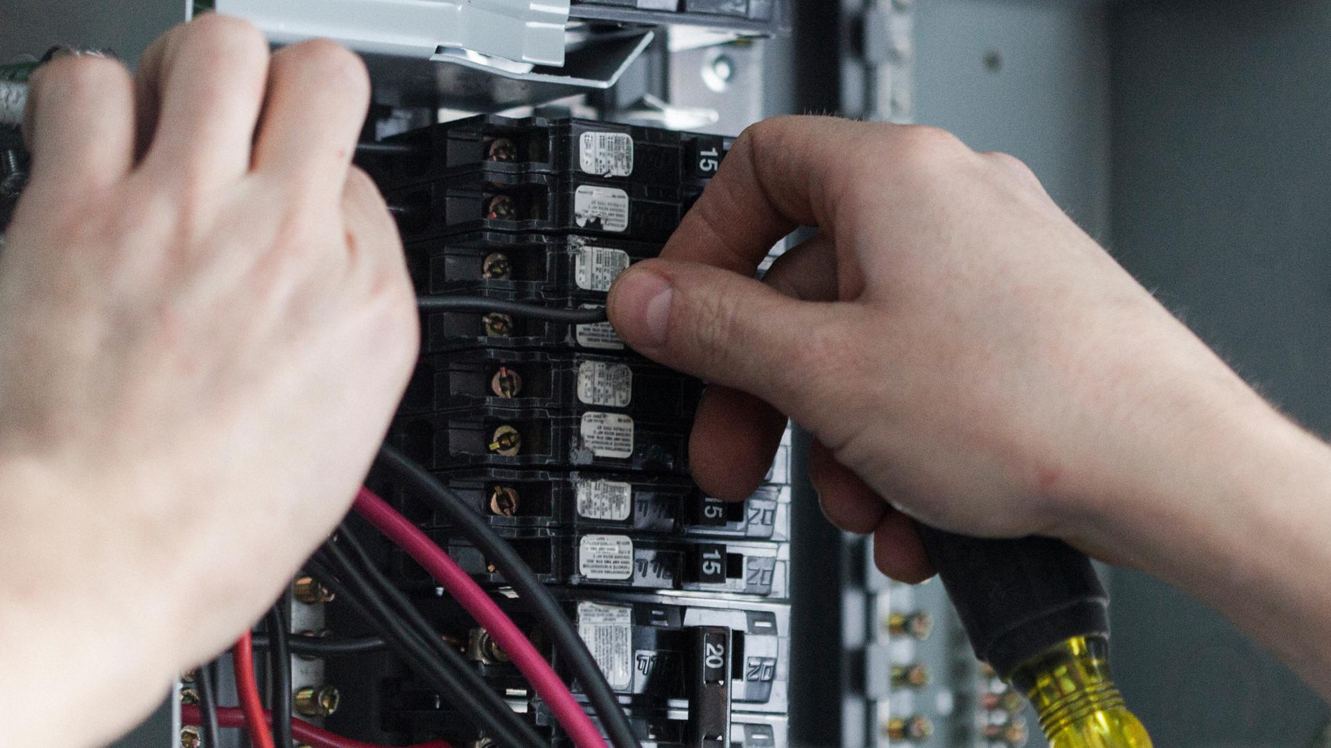 An electrician working inside a fuse box
